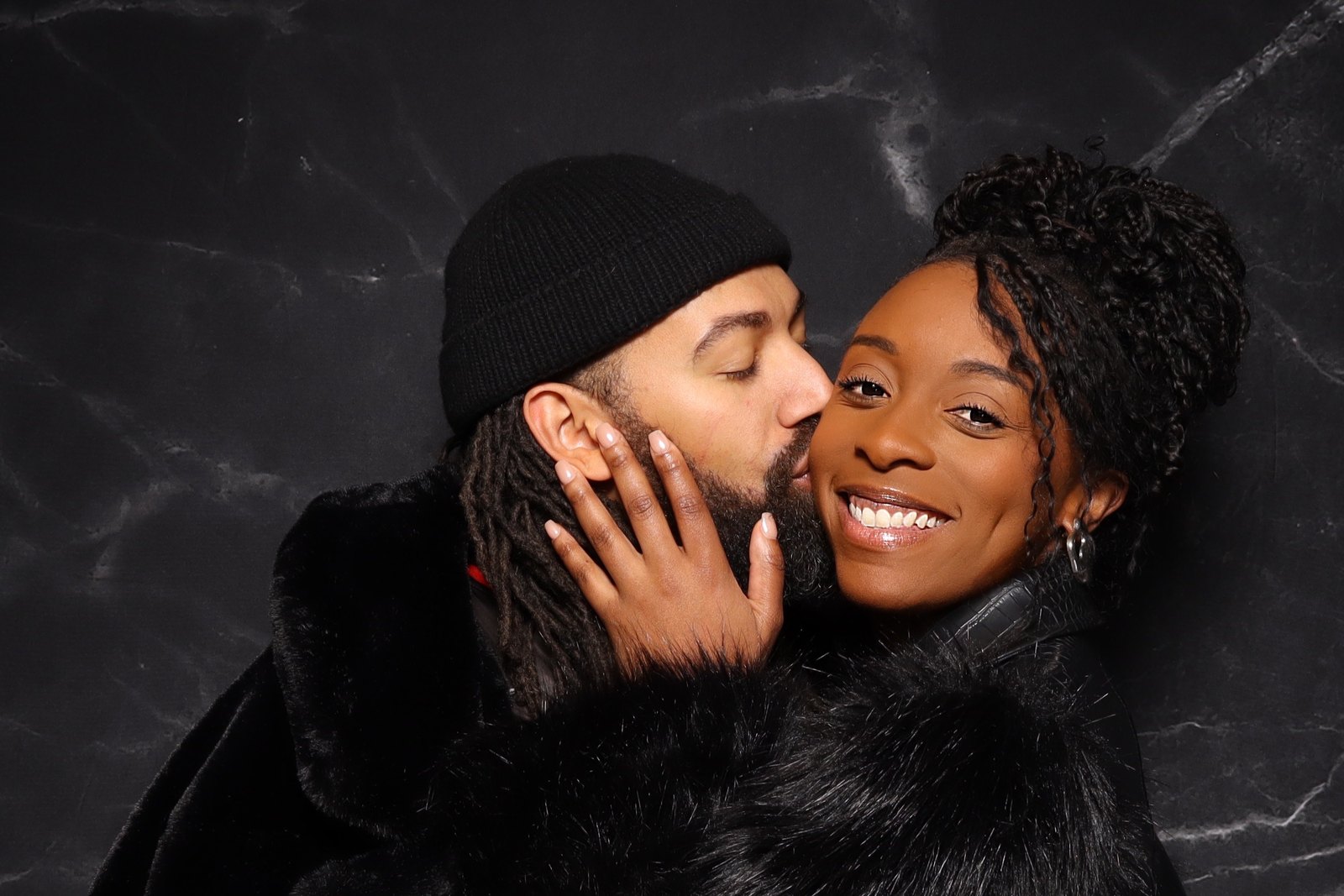 A couple photographed against a black marble backdrop.