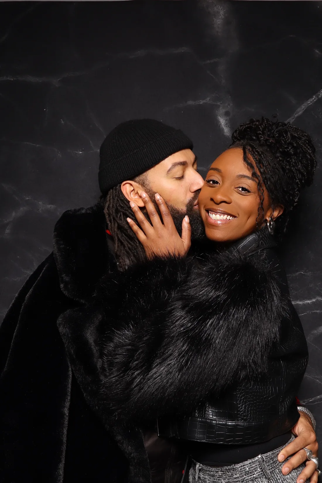 A couple photographed against a black marble backdrop.