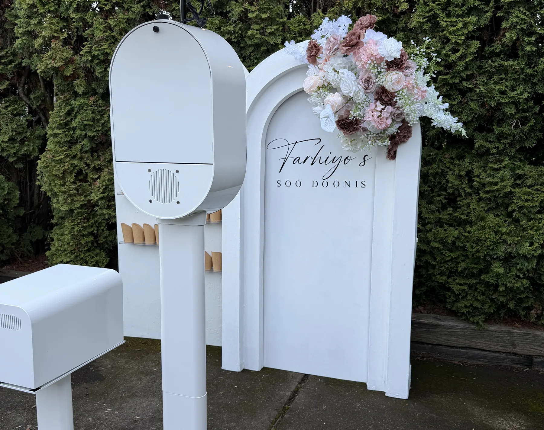 The photo booth set up outdoors beside a floral arrangement.